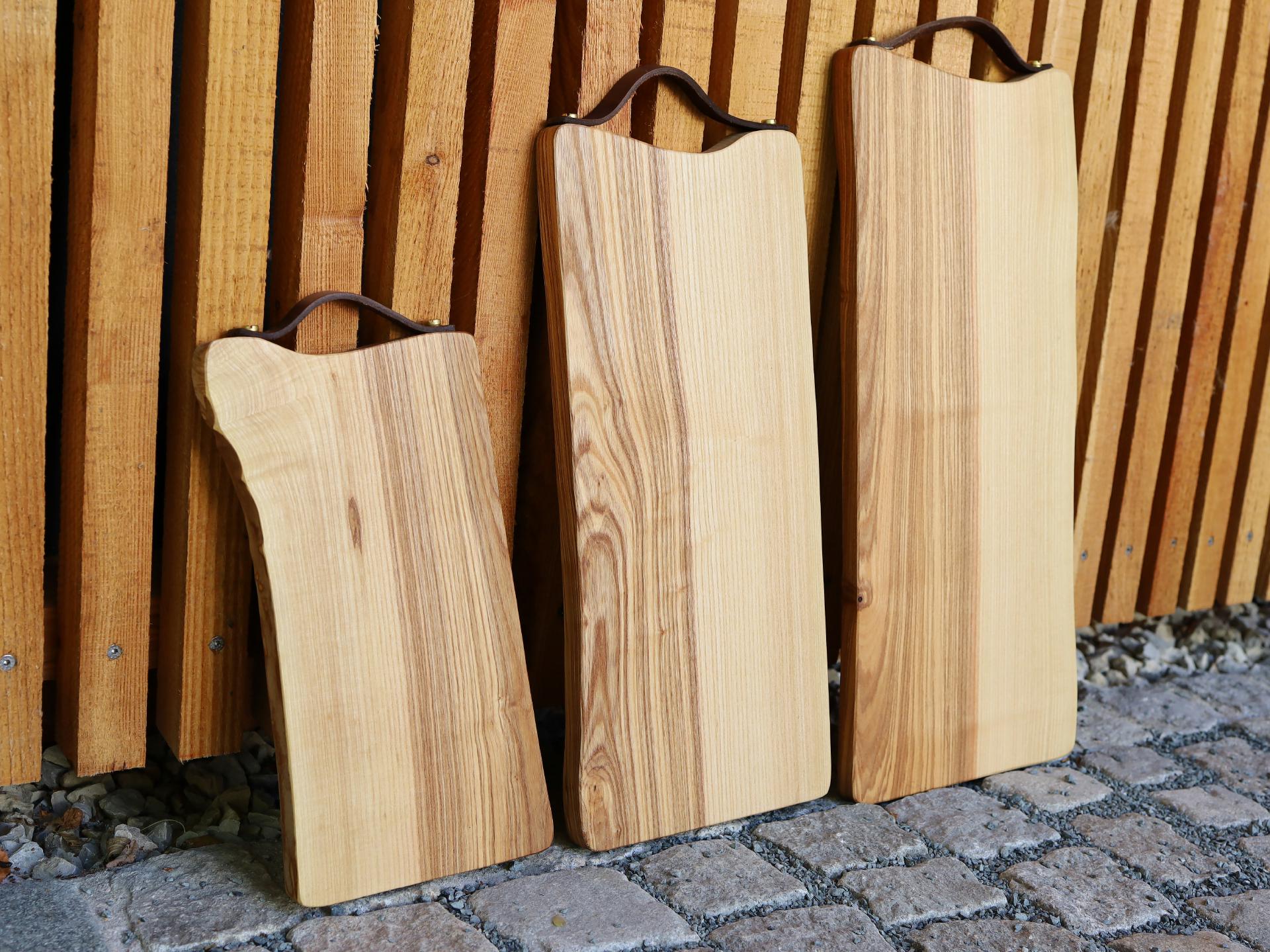 Schneidebrett aus geölter Esche 50x24 cm mit Baumkante und Ledergriff
