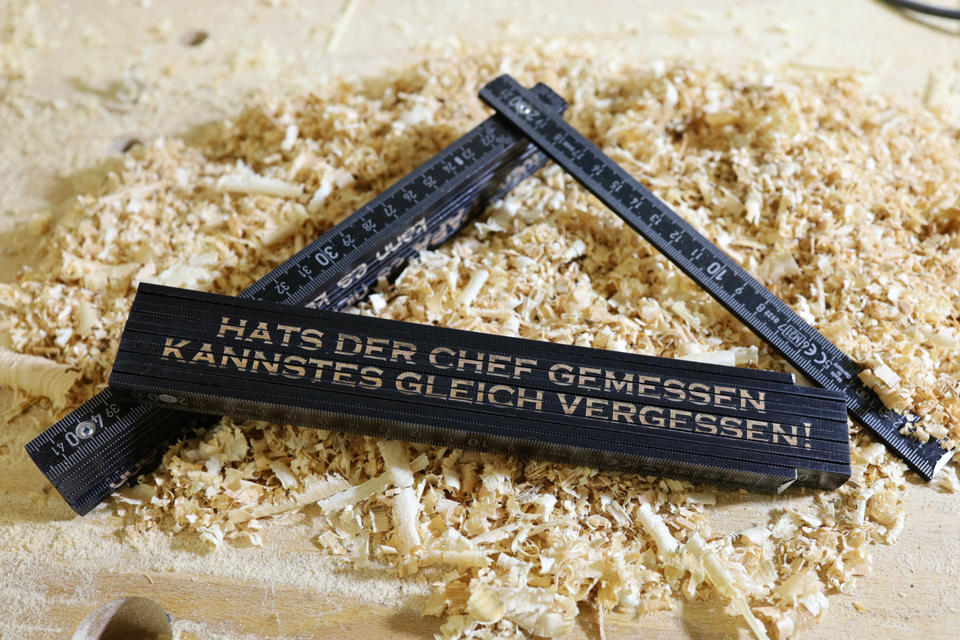 Schwarzer Zollstock 2m mit Chef-Spruch „Hats der Chef gemessen“
